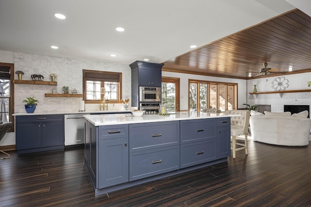 kitchen featuring dark wood-type flooring, a kitchen island, stainless steel dishwasher, and blue cabinetry