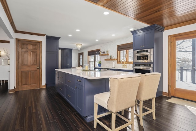 kitchen with sink, a breakfast bar, dark hardwood / wood-style floors, a center island, and stainless steel double oven