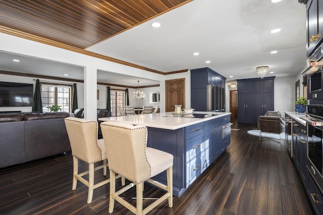 kitchen featuring wood ceiling, a breakfast bar area, a center island, blue cabinets, and a chandelier