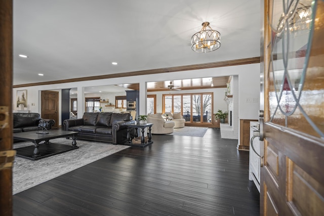 living room with crown molding, dark wood-type flooring, and a chandelier