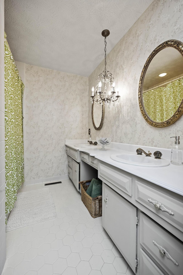 bathroom with tile patterned flooring, vanity, a notable chandelier, and a textured ceiling