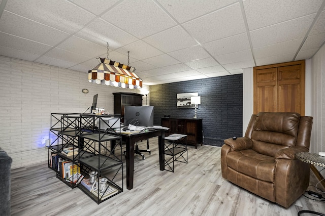 dining space featuring a paneled ceiling, brick wall, and hardwood / wood-style floors