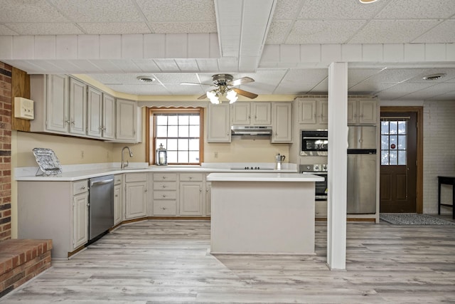 kitchen featuring sink, ceiling fan, stainless steel appliances, a kitchen bar, and light wood-type flooring