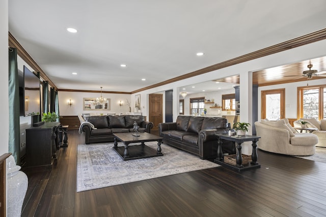 living room featuring crown molding, dark wood-type flooring, and ceiling fan with notable chandelier