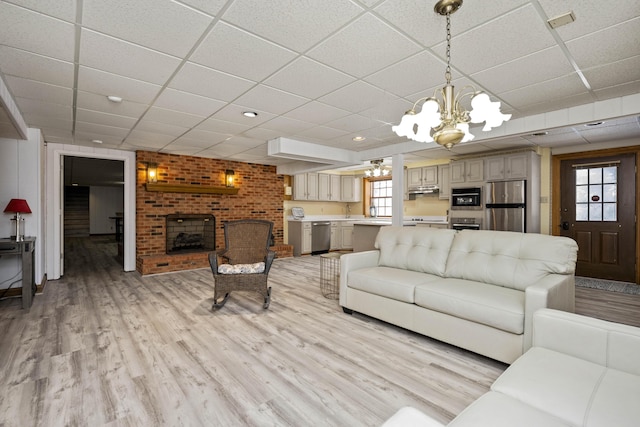 living room featuring a paneled ceiling, a fireplace, and light hardwood / wood-style floors