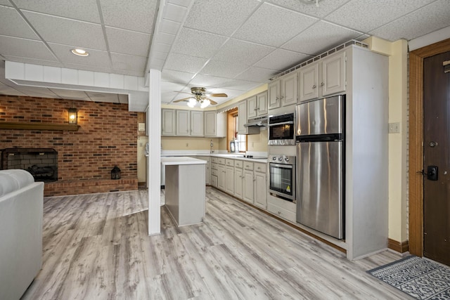 kitchen featuring ceiling fan, a paneled ceiling, stainless steel appliances, and light wood-type flooring