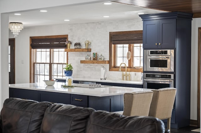 kitchen featuring blue cabinets, sink, tasteful backsplash, a center island, and a wealth of natural light