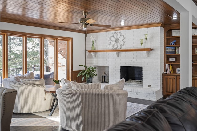 living room featuring wood ceiling, ornamental molding, a fireplace, and wood walls