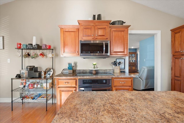 kitchen featuring light hardwood / wood-style flooring, black appliances, and vaulted ceiling