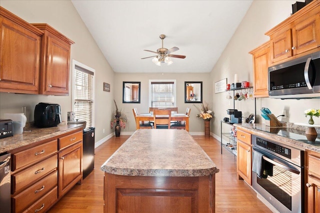 kitchen with lofted ceiling, stainless steel appliances, a kitchen island, and plenty of natural light