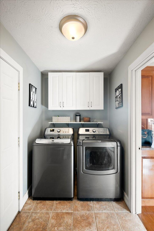 washroom featuring washer and clothes dryer, cabinets, a textured ceiling, and light tile patterned flooring