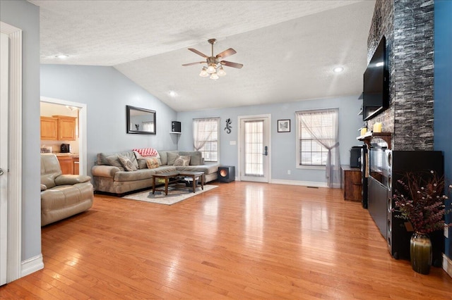 living room with lofted ceiling, plenty of natural light, a textured ceiling, and light hardwood / wood-style floors