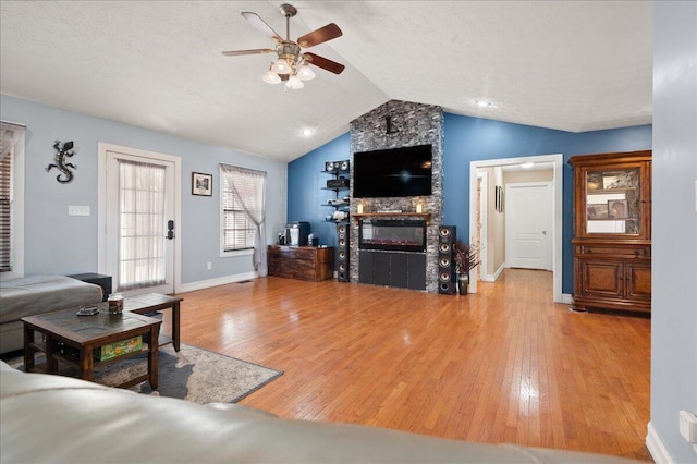 living room with wood-type flooring, lofted ceiling, a textured ceiling, and a fireplace