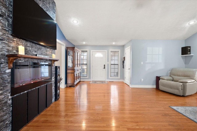 entryway featuring a stone fireplace, a textured ceiling, and light hardwood / wood-style flooring