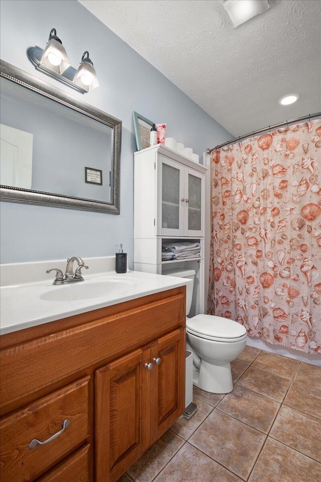 bathroom with toilet, a textured ceiling, vanity, curtained shower, and tile patterned flooring