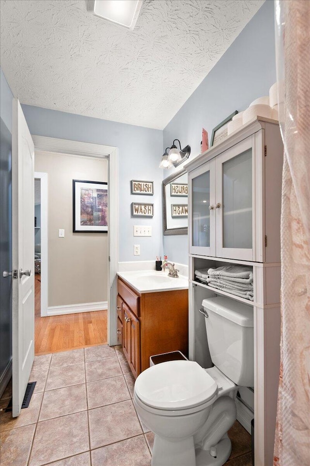 bathroom featuring vanity, toilet, tile patterned flooring, and a textured ceiling