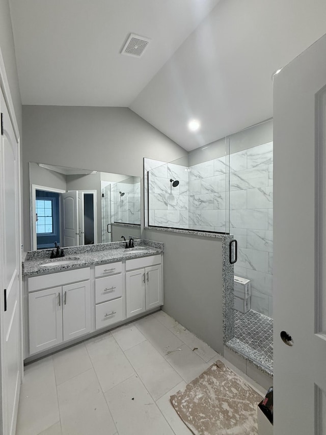 bathroom featuring vanity, a shower with shower door, and vaulted ceiling