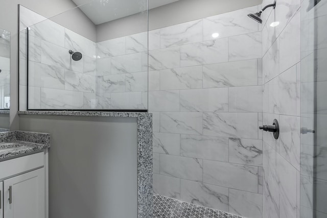 bathroom with a tile shower and vanity