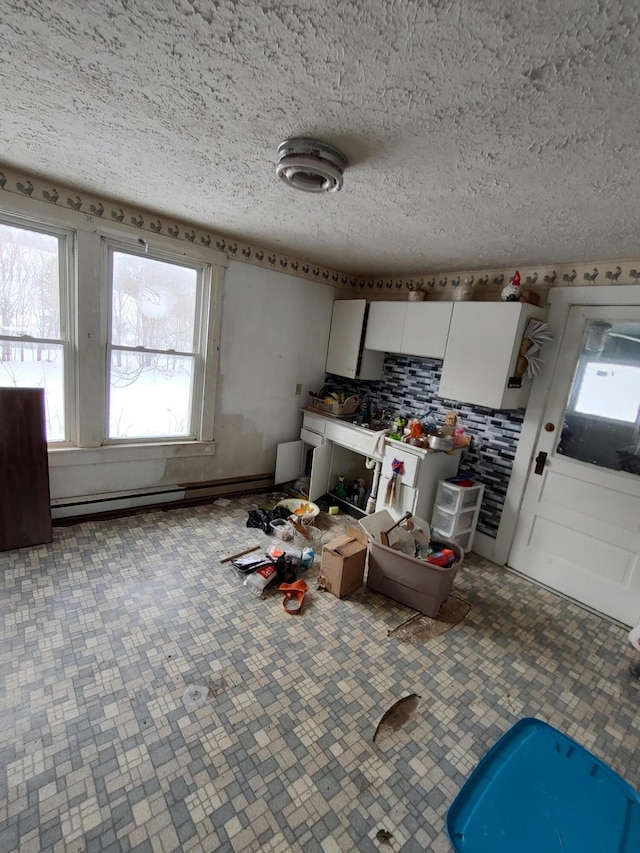 kitchen featuring white cabinets, a textured ceiling, and baseboard heating