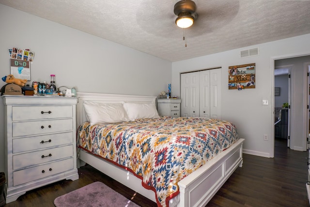 bedroom with dark hardwood / wood-style flooring, a textured ceiling, ceiling fan, and a closet