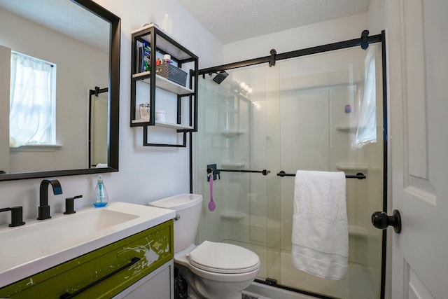 bathroom with vanity, a shower with shower door, toilet, and a textured ceiling