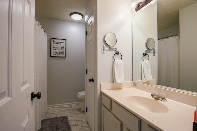 bathroom featuring vanity, toilet, and a textured ceiling