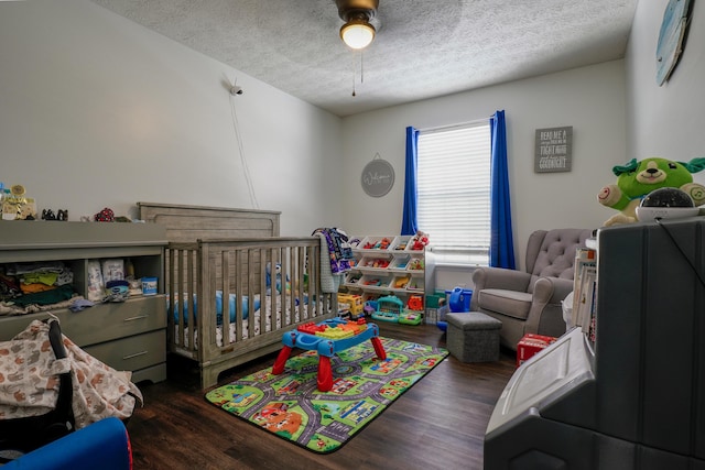 bedroom featuring dark hardwood / wood-style flooring, a textured ceiling, and a crib