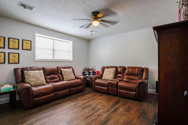 living room featuring dark wood-type flooring, a textured ceiling, and ceiling fan