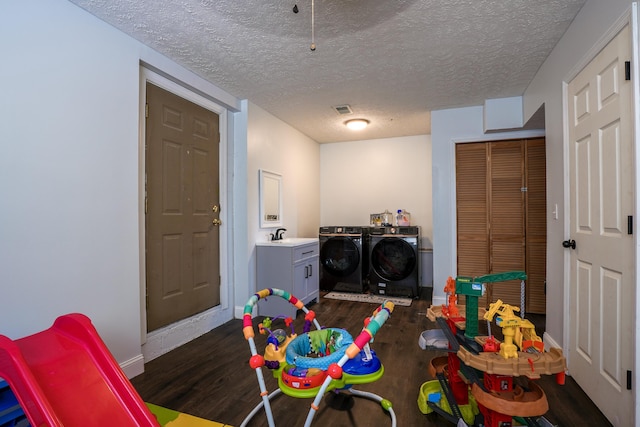 game room with washing machine and clothes dryer, dark hardwood / wood-style flooring, and a textured ceiling