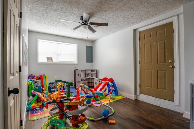 rec room with ceiling fan, dark hardwood / wood-style floors, electric panel, and a textured ceiling