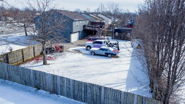 yard covered in snow with a wooden deck and a garage