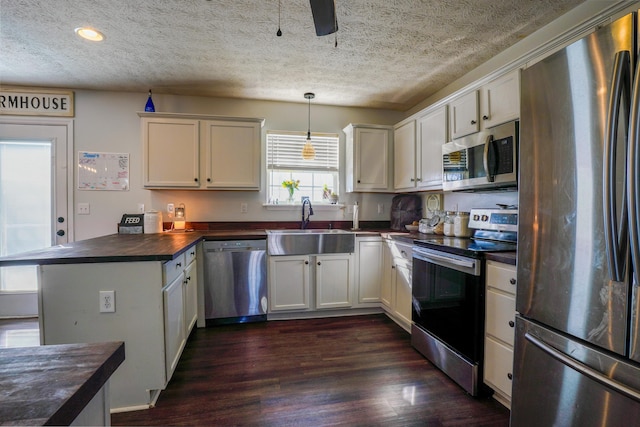 kitchen featuring dark hardwood / wood-style floors, sink, white cabinets, hanging light fixtures, and stainless steel appliances