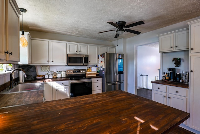 kitchen with pendant lighting, sink, white cabinets, ceiling fan, and stainless steel appliances