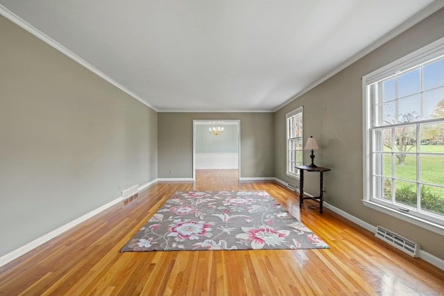 interior space featuring a notable chandelier, plenty of natural light, ornamental molding, and light hardwood / wood-style floors