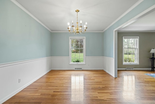 spare room with ornamental molding, light wood-type flooring, and a chandelier