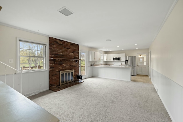 unfurnished living room with ornamental molding, light carpet, and a fireplace