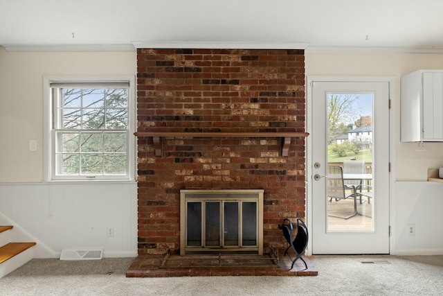 unfurnished living room featuring crown molding, carpet, wooden walls, and a fireplace