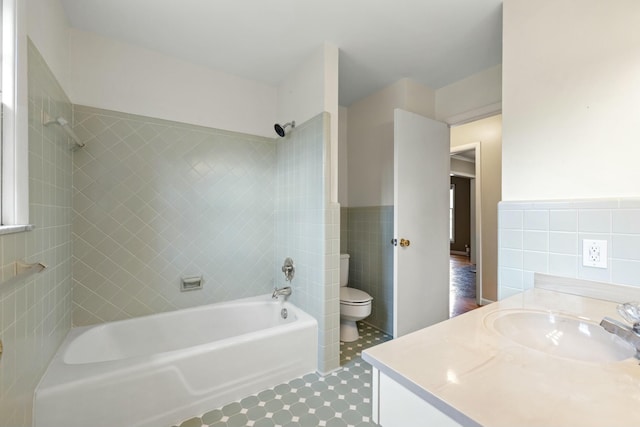 full bathroom featuring tiled shower / bath combo, vanity, tile walls, and toilet