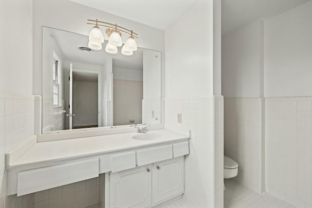 bathroom with tile patterned flooring, vanity, tile walls, and toilet