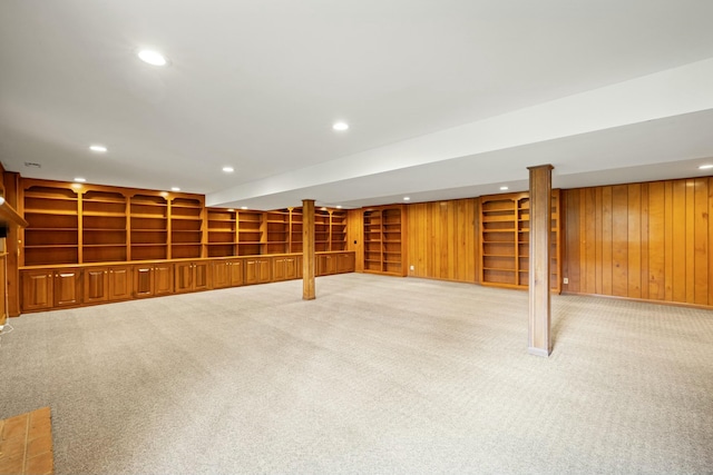 basement with light carpet, built in features, and wood walls