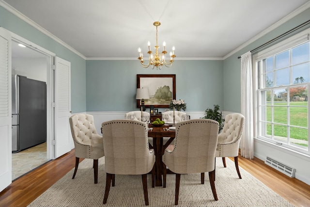 dining space featuring crown molding, plenty of natural light, light hardwood / wood-style flooring, and a notable chandelier