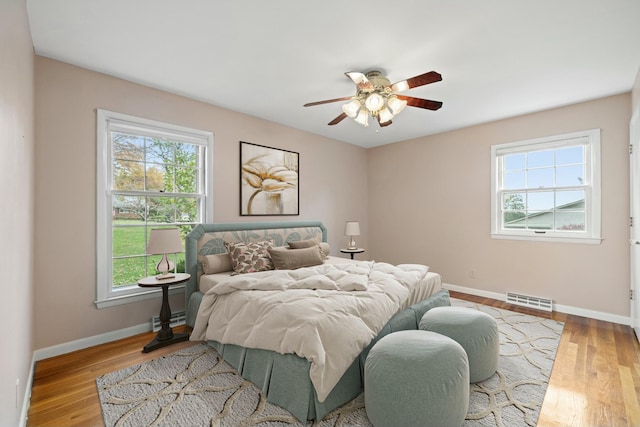 bedroom featuring multiple windows, ceiling fan, and light hardwood / wood-style flooring