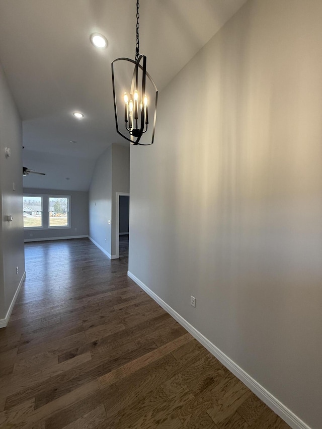 unfurnished dining area with dark wood-type flooring, lofted ceiling, and ceiling fan with notable chandelier