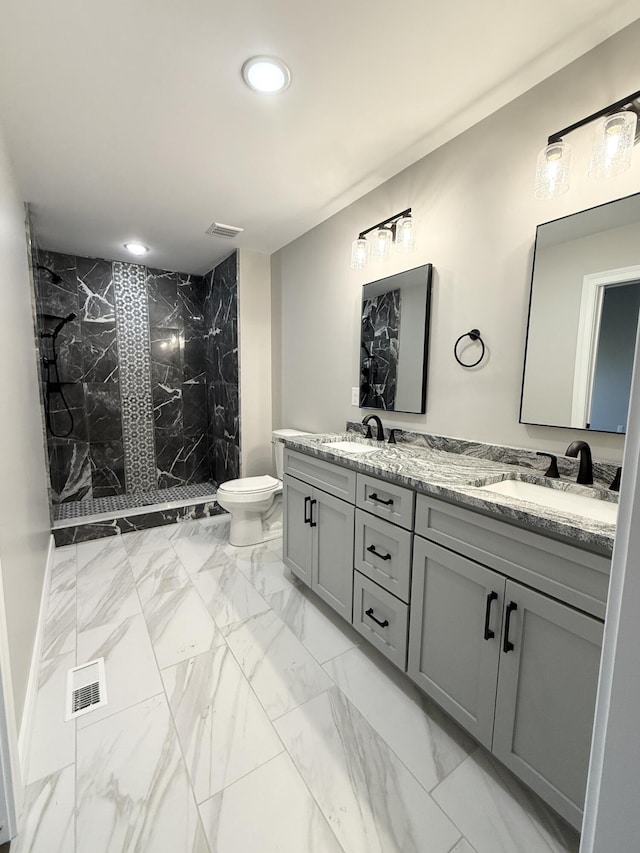 bathroom featuring tiled shower, vanity, and toilet