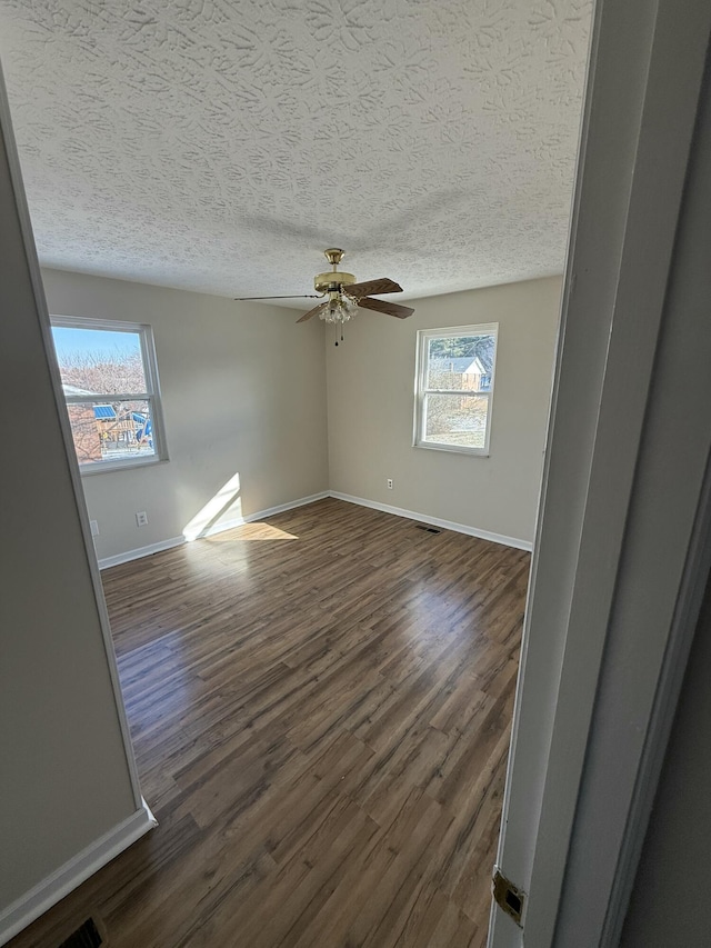 spare room with dark wood-type flooring, ceiling fan, and a textured ceiling