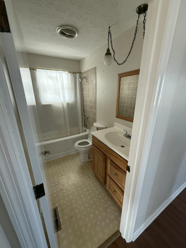 full bathroom with vanity, tiled shower / bath, a textured ceiling, and toilet