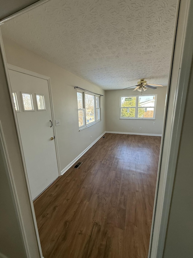 entrance foyer featuring ceiling fan, plenty of natural light, dark hardwood / wood-style flooring, and a textured ceiling