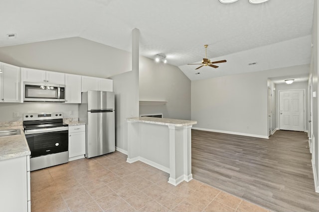 kitchen featuring lofted ceiling, ceiling fan, stainless steel appliances, white cabinets, and kitchen peninsula