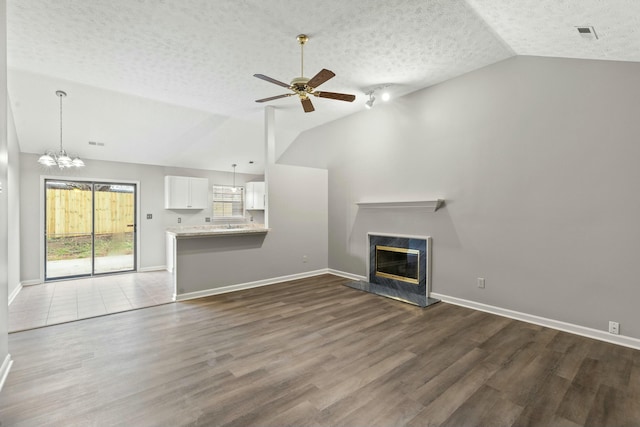 unfurnished living room featuring dark wood-type flooring, vaulted ceiling, and a high end fireplace