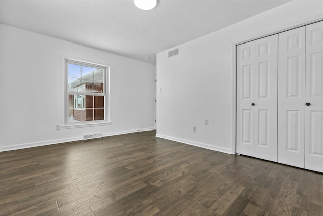 unfurnished bedroom with dark hardwood / wood-style flooring and a closet